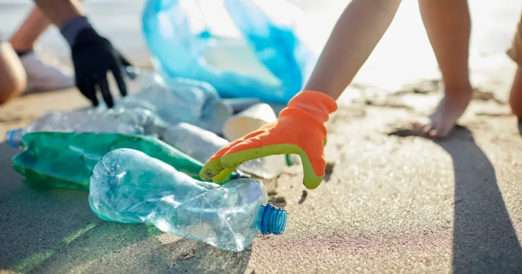 close-up of hands, feet and plastic bottles being cleaned up off the beach